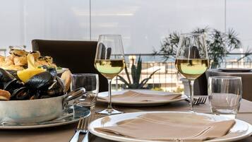 Mesa posta com amêijoas, pão e copos de vinho.