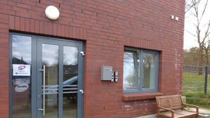 A building with a glass door, a bench outside, and a window. - Hotel Hansehus Süd (Hamburg)