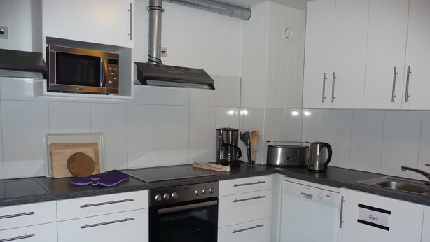 A modern kitchen with white cabinets, a built-in microwave, a stove, and a dishwasher. - Hotel Hansehus Süd (Hamburg)