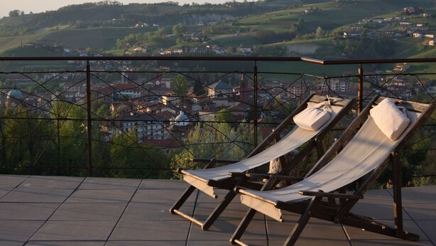 Une terrasse dotée de deux fauteuils confortables, offrant une vue panoramique sur une ville et des collines.