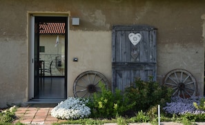 A rustic building with a door, two decorative wheels, and a heart-shaped ornament. - CasaMatilda Agriturismo Langhe (Dogliani)