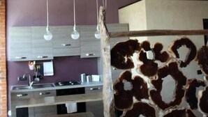 Une cuisine moderne dotée d’un îlot central, de luminaires suspendus et d’un mur décoratif en bois rustique.
