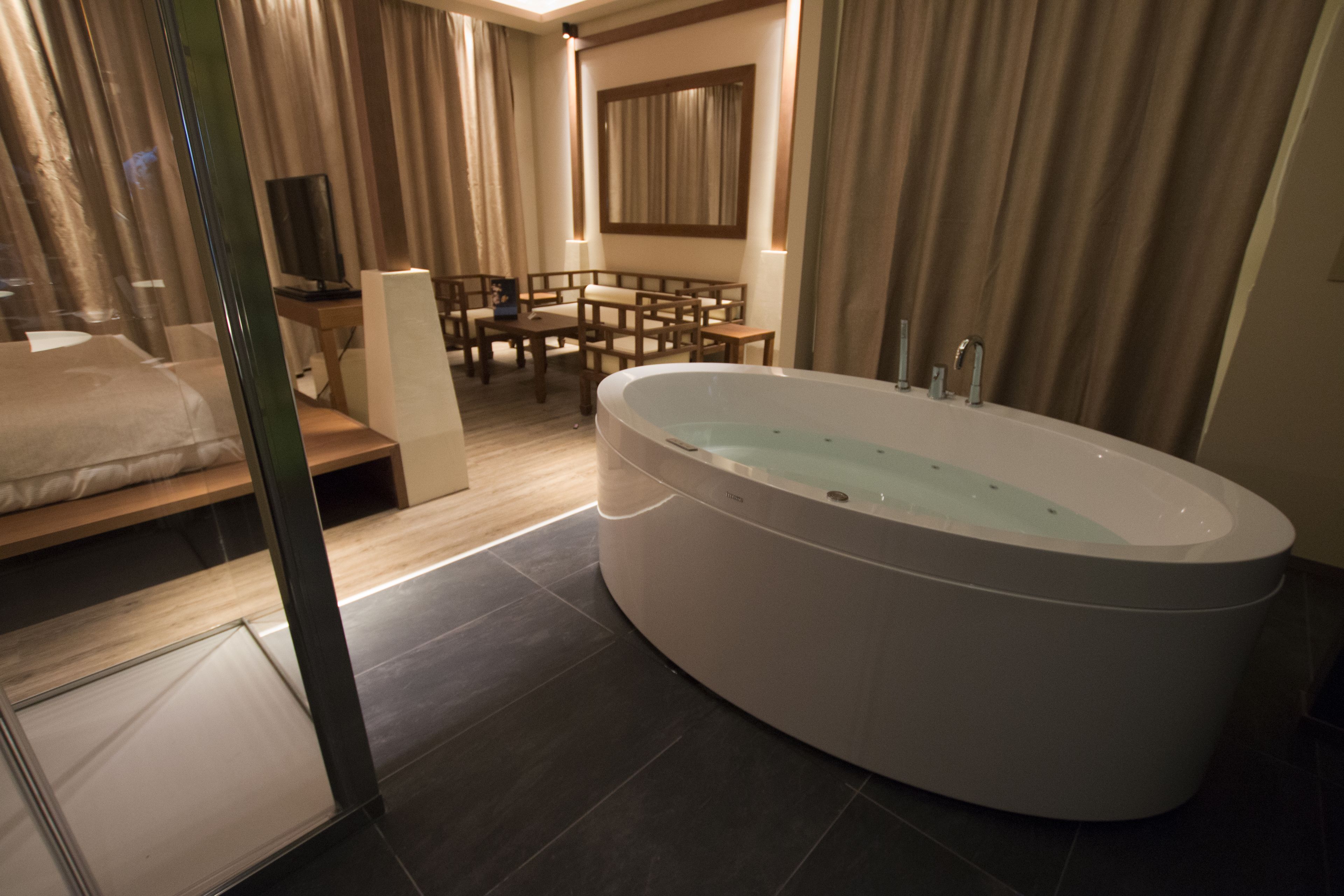 A modern bathroom with a freestanding bathtub, a wooden vanity, and a seating area with a table and chairs.