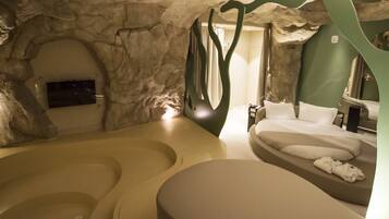 A spa room with a large bathtub, a sofa bed, and a television.