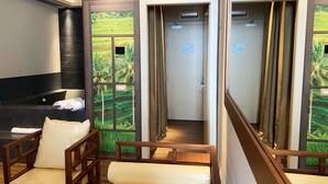 Une chambre d’hôtel moderne dotée d’un comptoir de réception, d’une salle de bain privée avec vue sur un paysage verdoyant et d’un coin salon avec des meubles en bois.