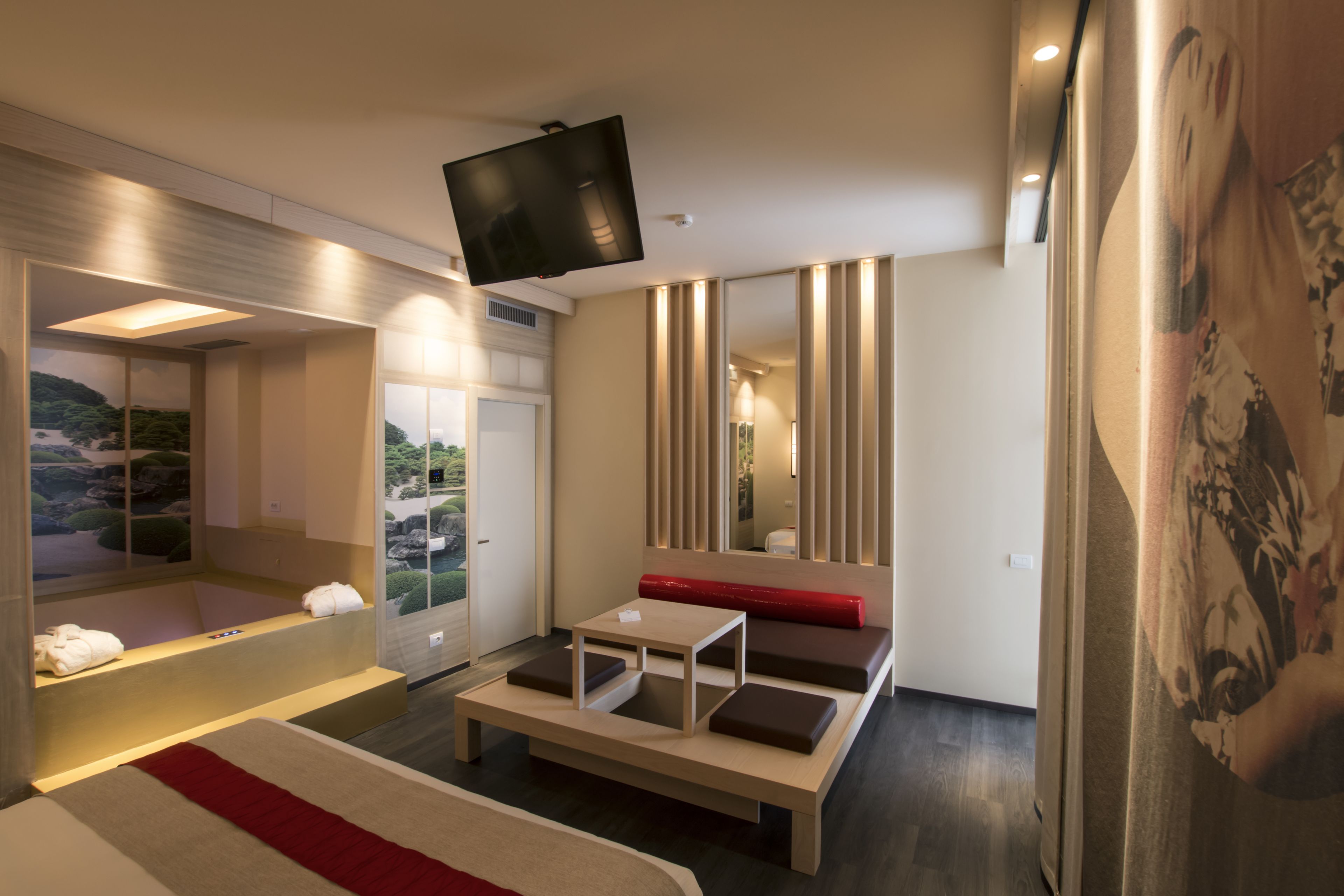Una habitación de hotel moderna con una cama grande, una mesita, un sofá, un televisor y un baño con bañera.