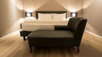 Un dormitorio con cama, mesitas de noche, una silla y una mesita auxiliar.