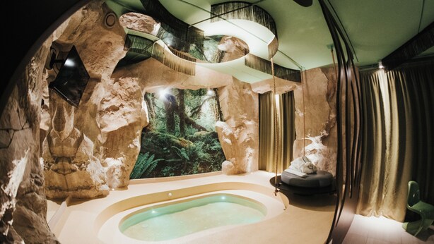 Une salle de spa dotée d’une grande baignoire, d’une fresque murale sur le thème de la forêt et d’un design moderne.