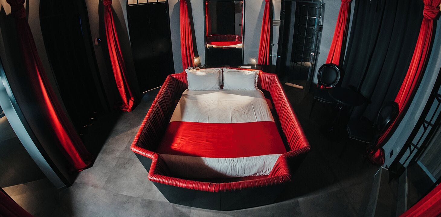 Un dormitorio moderno con una cama grande, cortinas rojas y un espejo.