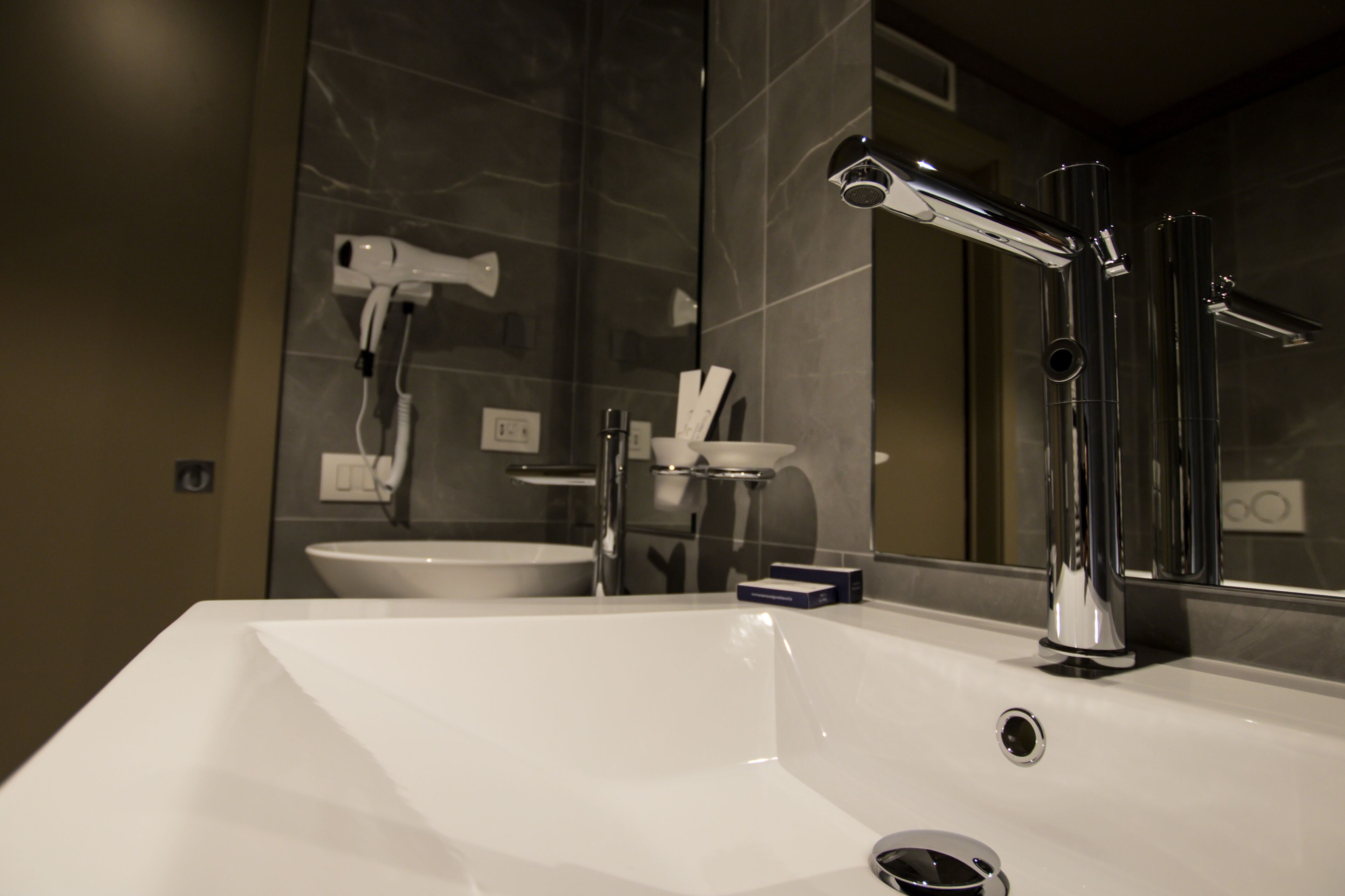 A modern bathroom with a white sink, chrome fixtures, and a large mirror.