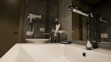A modern bathroom with a white sink, chrome fixtures, and a large mirror.