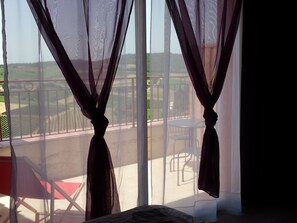 Una habitación con una ventana grande, una cama y una silla.