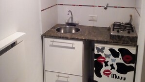 Een kleine keuken met een spoelbak, een fornuis en een magnetron.