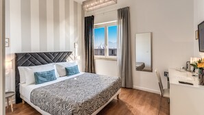 A modern hotel room with a large bed, a desk, and a view of the city. - Napoli Great View B&B (Naples)