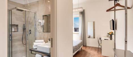 Une salle de bain moderne dotée d’une douche à parois de verre, d’un meuble-lavabo avec un évier et un porte-serviettes, et d’un lit offrant une vue sur l’extérieur.