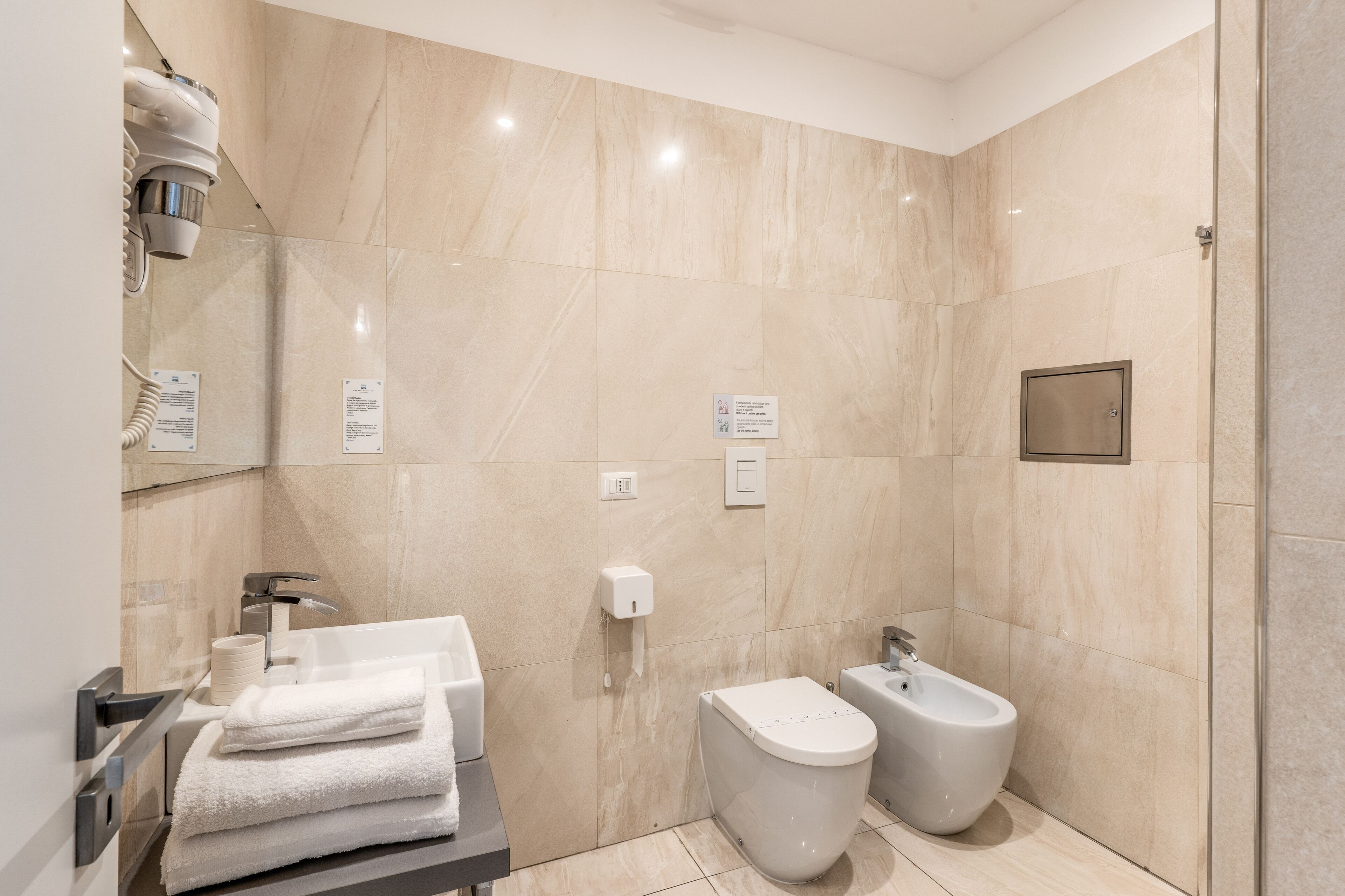 A modern bathroom with a toilet, bidet, and towel rack.