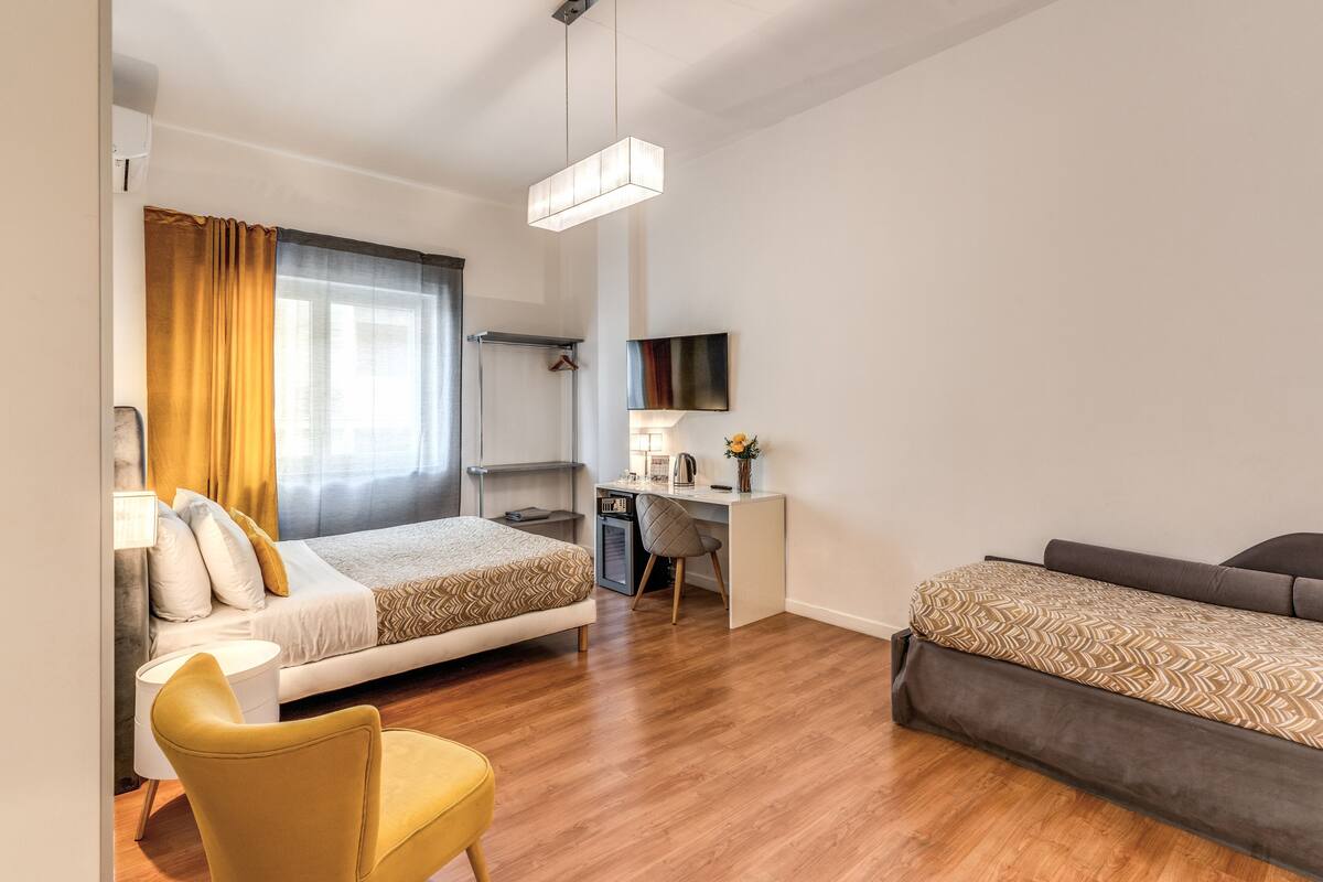 Et moderne hotelværelse med seng, skrivebord, stol og sofa.