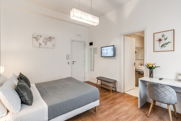 A modern bedroom with a bed, a desk, and a television.