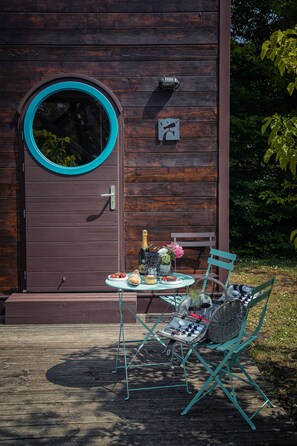 A wooden door with a circular window, a small table with a bottle, a chair, and a basket. - Carré d'Etoiles Paleine (Le Puy-Notre-Dame)