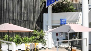 Un área de estar al aire libre con sombrillas, sillas amarillas y un letrero para hoteles ibis budget.