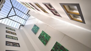 Un techo alto con tragaluces y obras de arte enmarcadas.