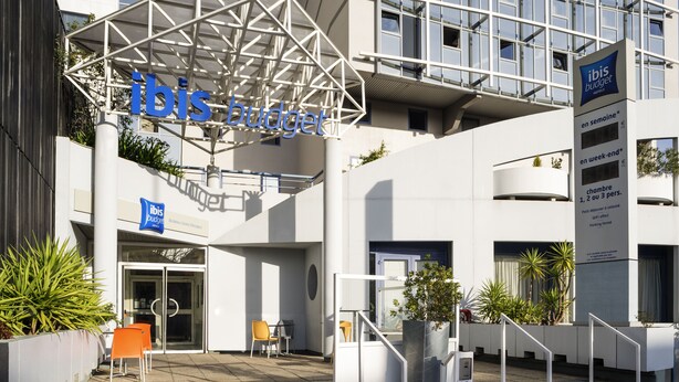 Una entrada de hotel moderna con un letrero que dice 'ibis budget' y una escalera que lleva a la entrada.