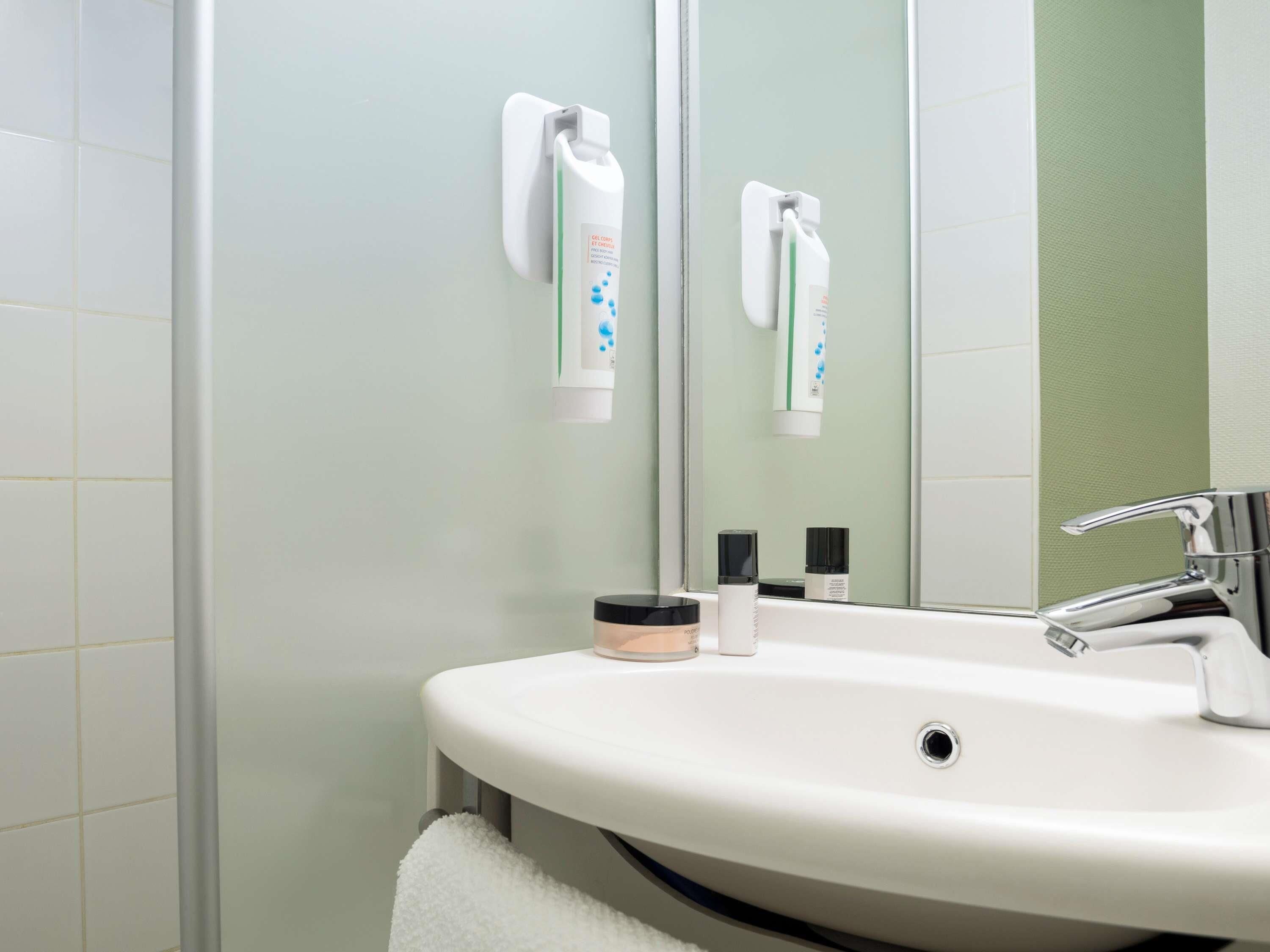 Un baño con un lavamanos blanco, un espejo y un perchero para toallas.
