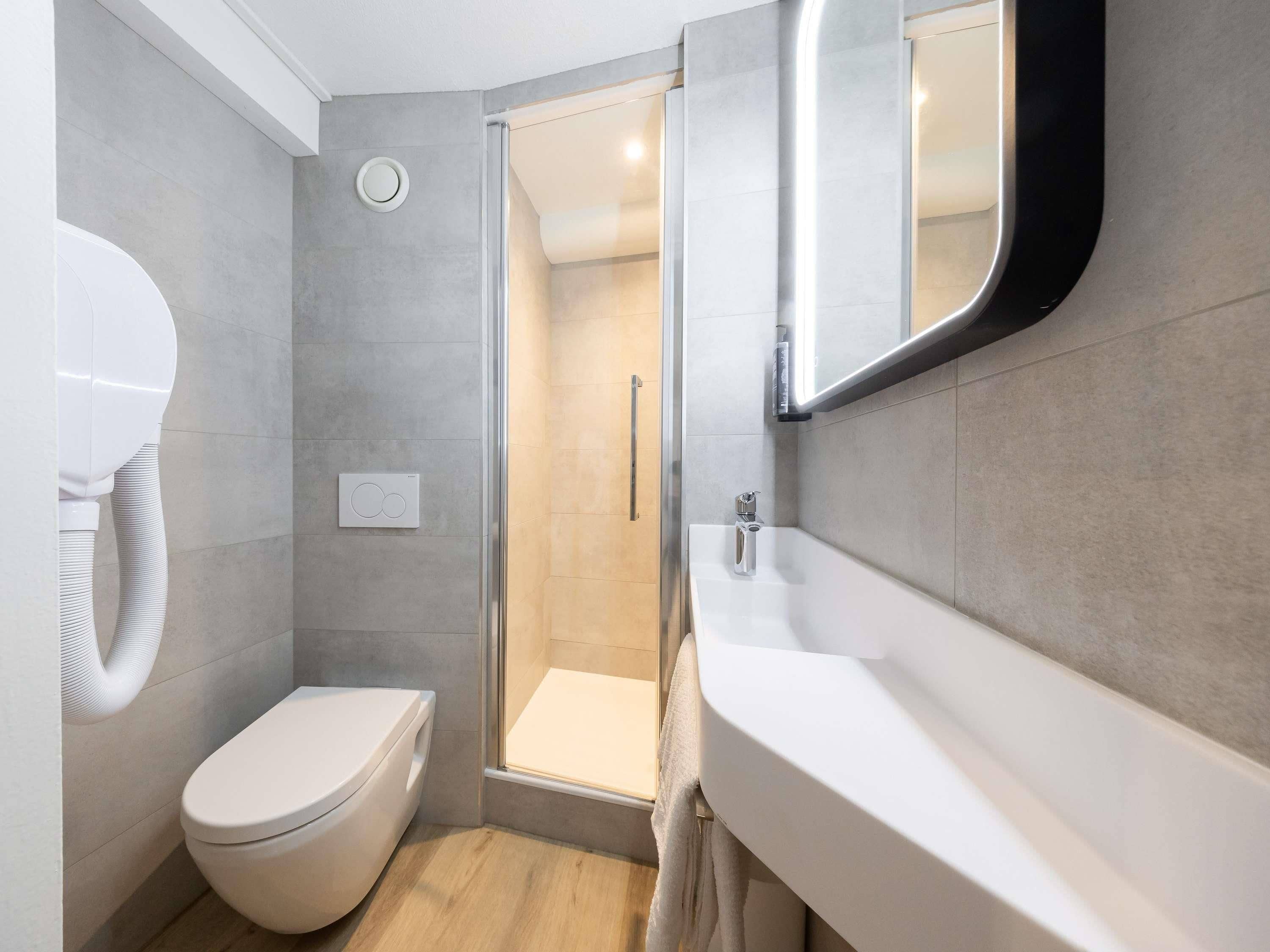 Un baño moderno con inodoro, ducha y lavamanos.