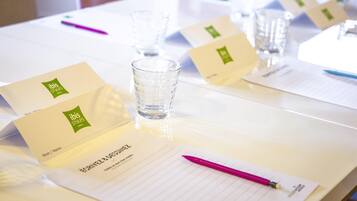 Una mesa de conferencias con tarjetas de identificación, un vaso de agua y un bloc de notas con un bolígrafo.