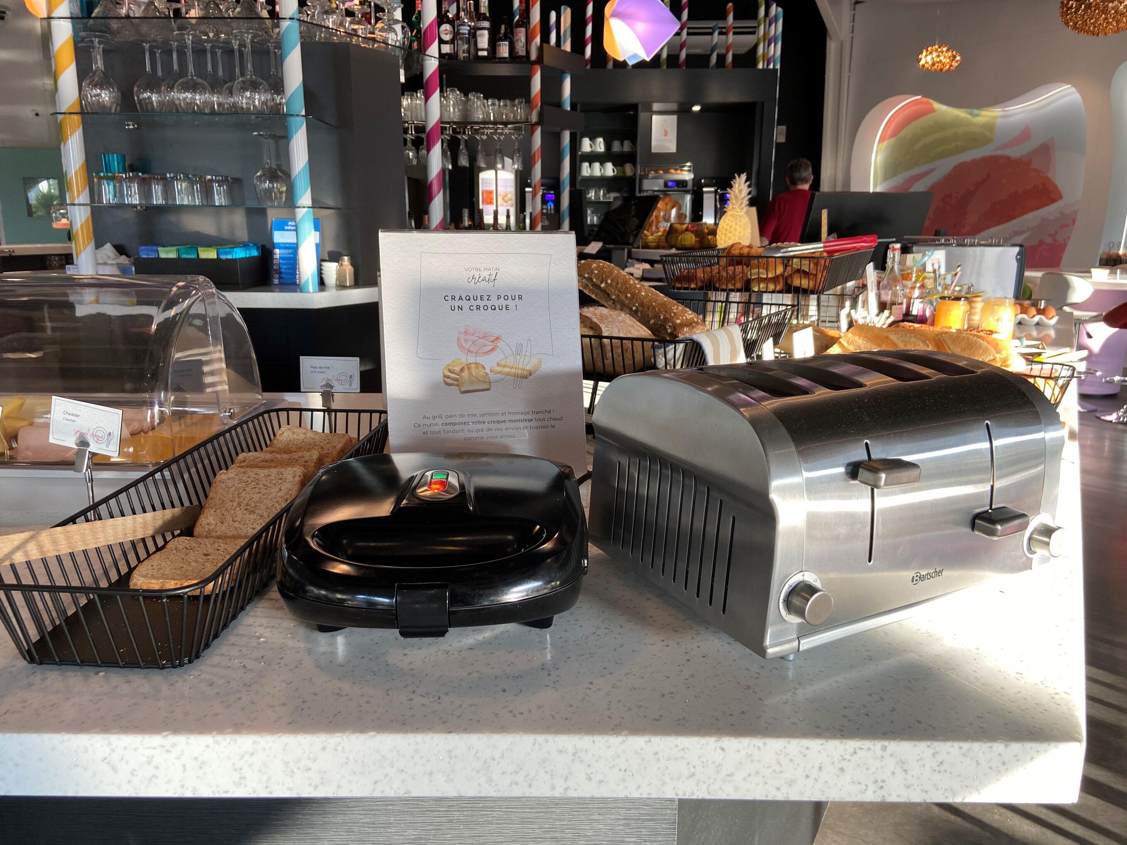 A breakfast bar with a toaster, a bread basket, and a sign in French.