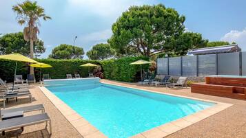 Una piscina al aire libre, sombrillas, tumbonas