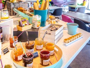 A variety of food items including jars of preserves and pastries on a counter.