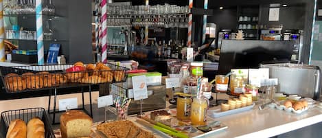 Mostrador de panadería con diversos productos horneados, pasteles y bebidas.