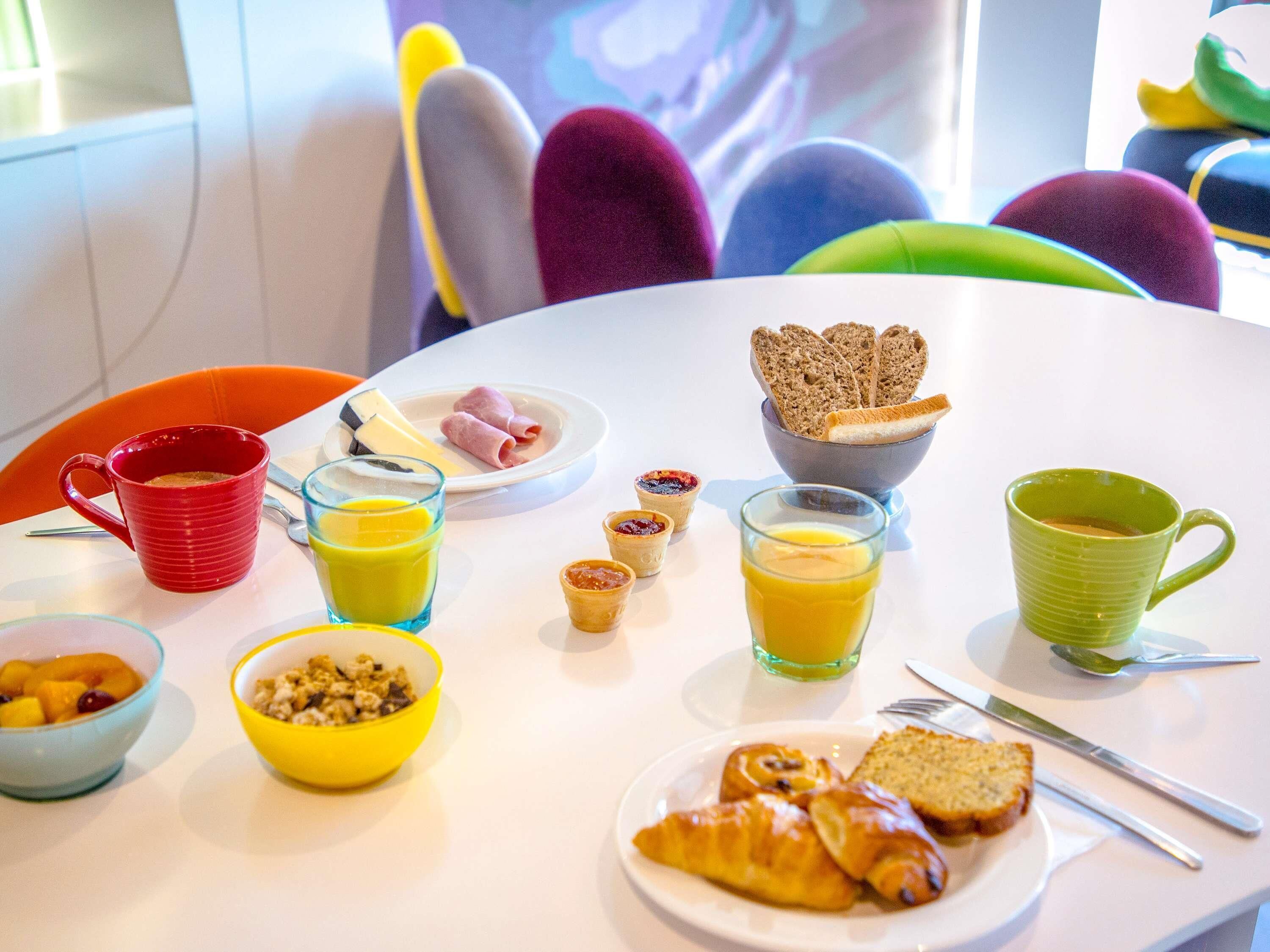 A breakfast table with various food items and drinks, including croissants, bread, and juice.