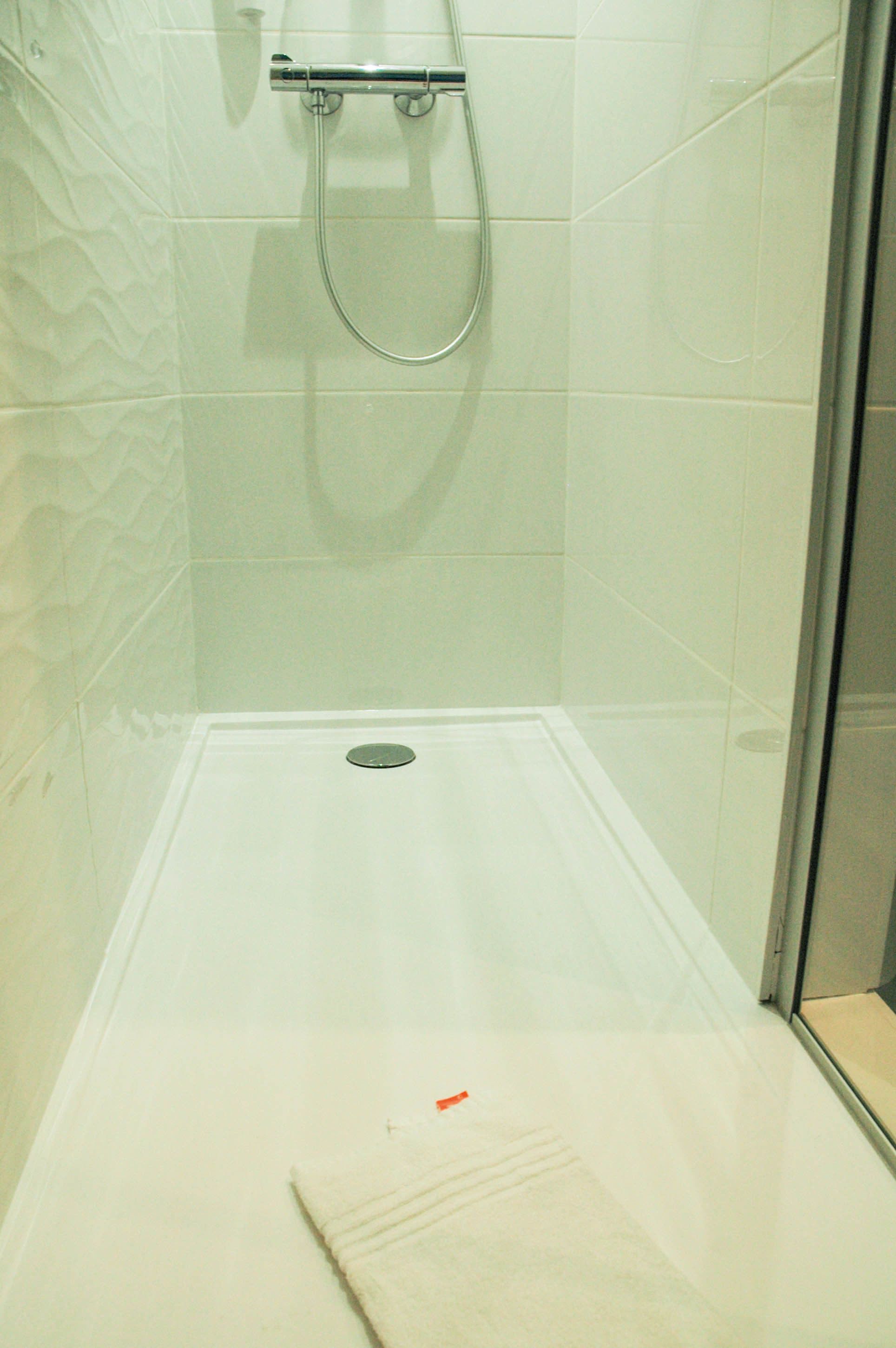 A small, enclosed shower area with a glass door and a metal showerhead.