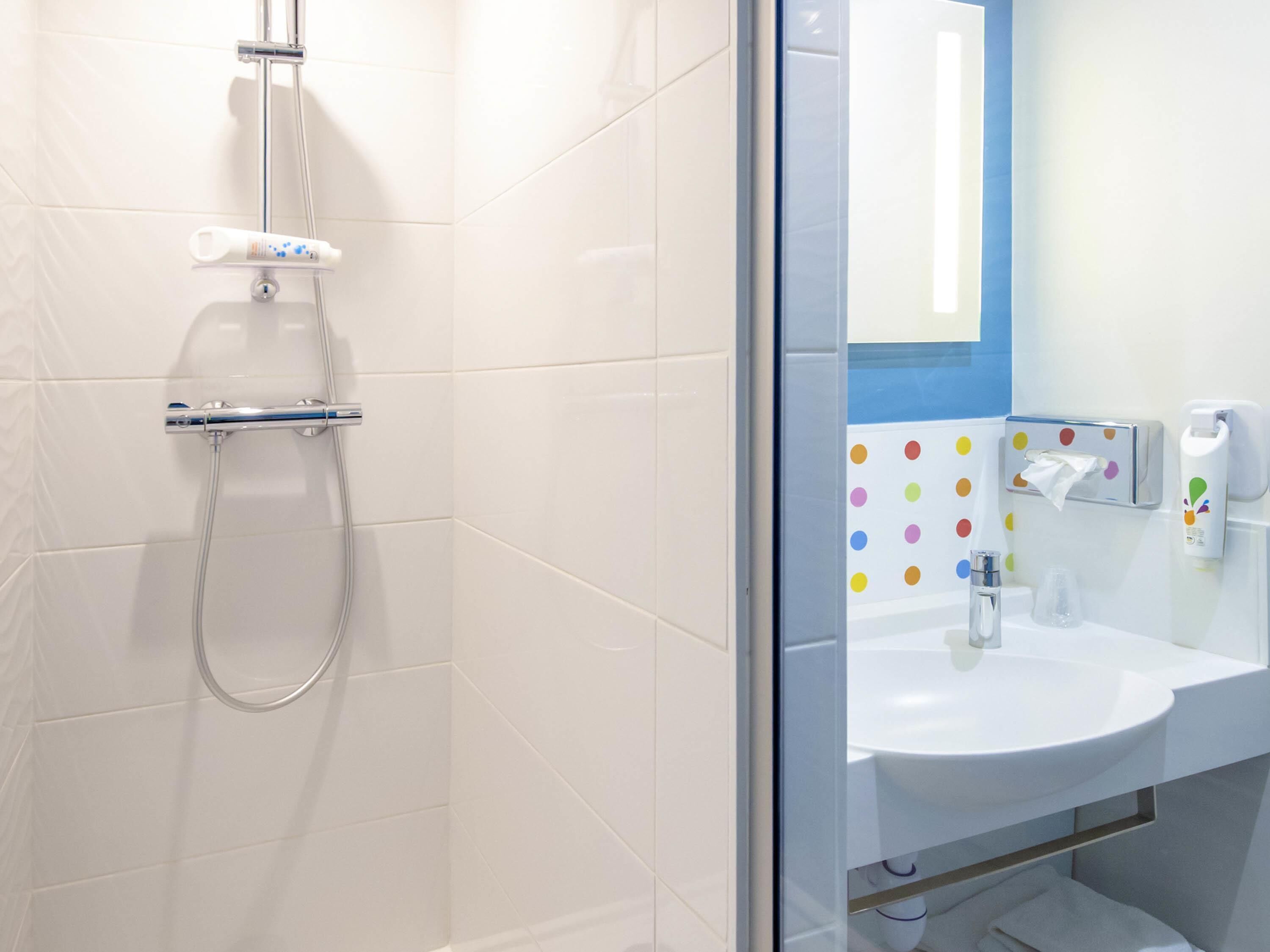 A bathroom with a shower, a sink, and a mirror.