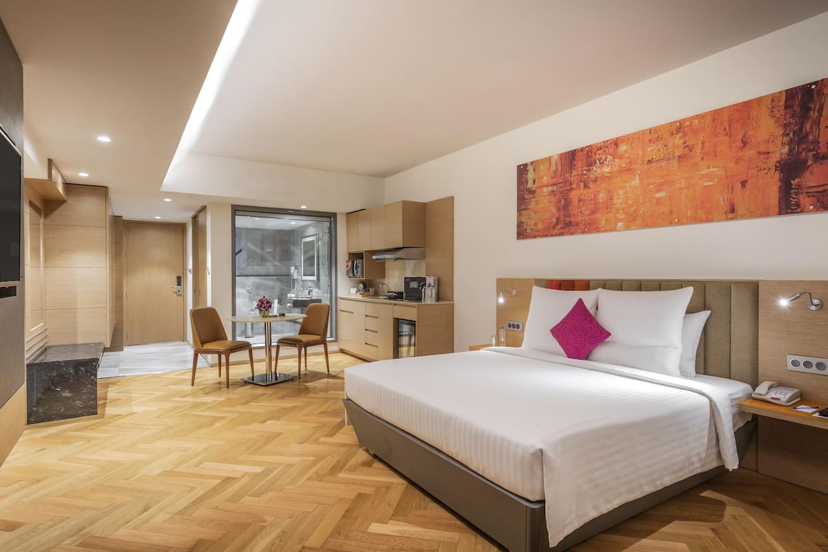 Een moderne hotelkamer met een groot bed, een bureau en een kitchenette.
