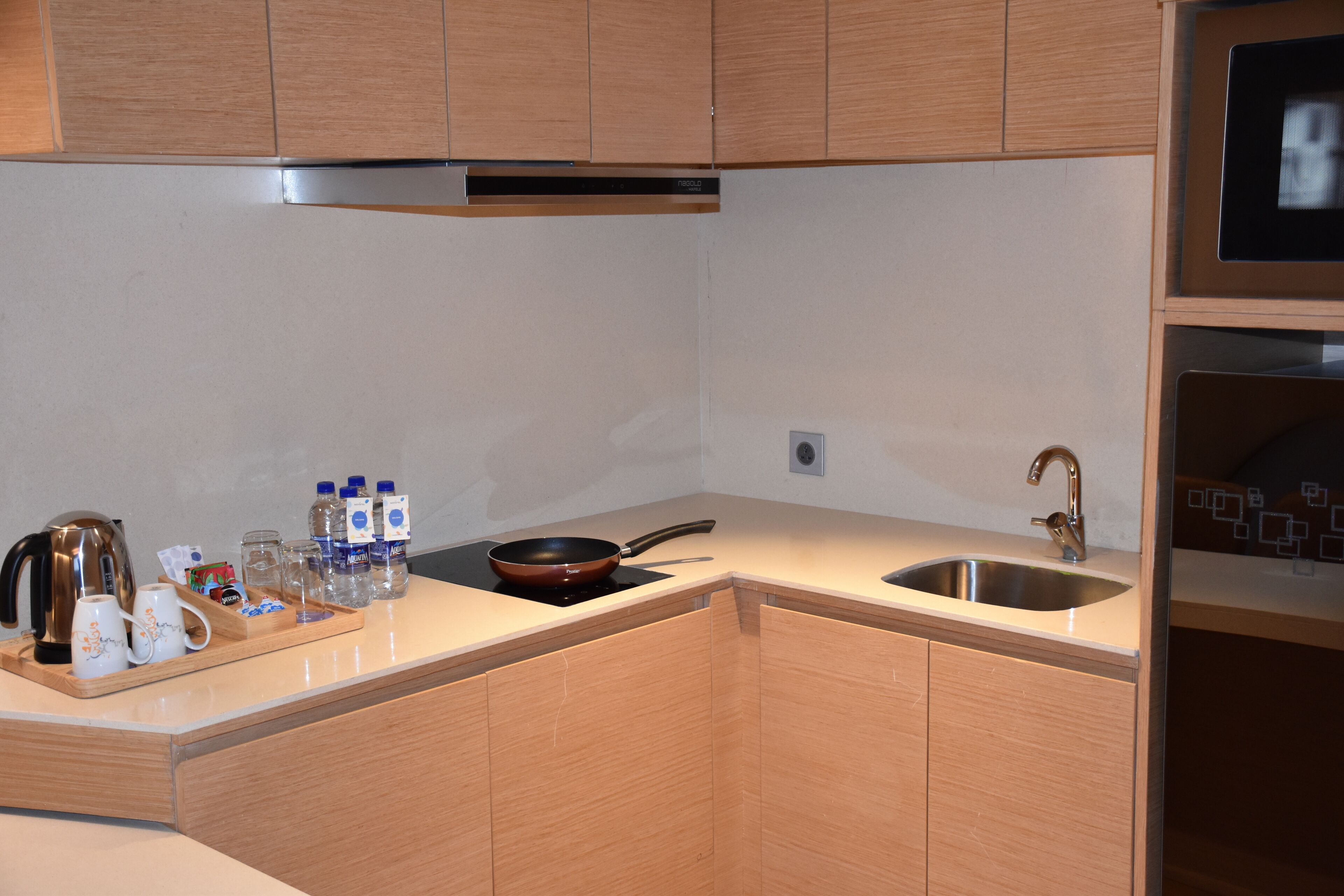 Una cocina moderna con armarios de madera, un lavamanos de acero inoxidable y una estufa empotrada.