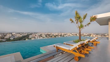 Una piscina al aire libre, sombrillas, sillones reclinables de piscina