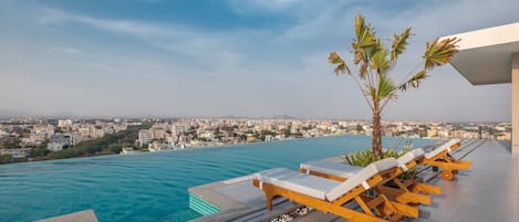 Una piscina al aire libre, sombrillas, sillones reclinables de piscina