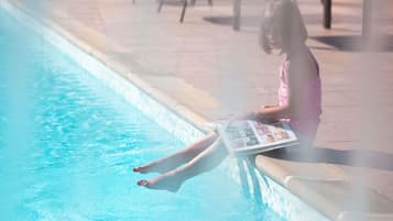 A person sitting by a pool with a magazine.
