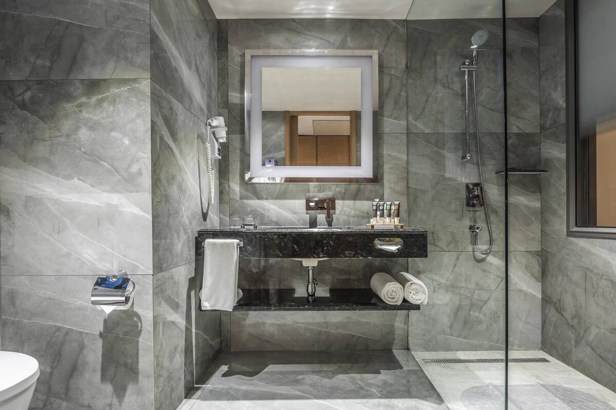 Un bagno moderno con pavimento in marmo, cabina doccia in vetro, mobile lavabo con specchio e servizi igienici.