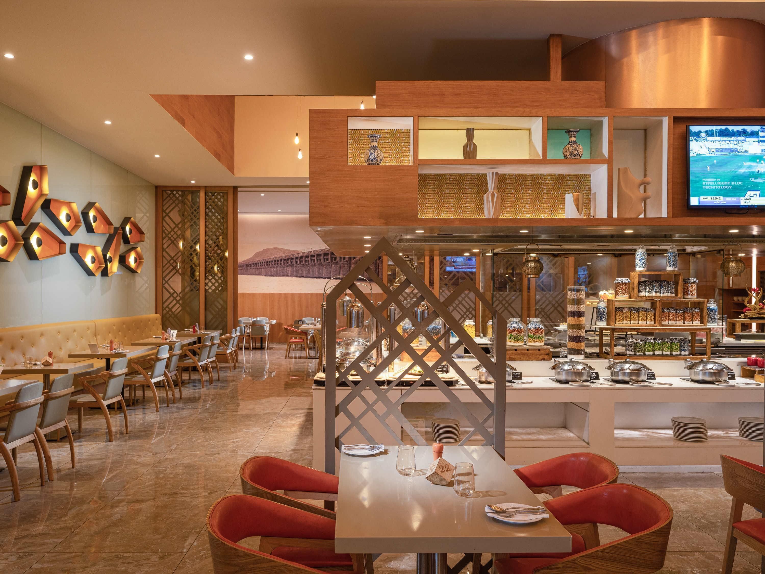 Un restaurante con zona de bar, distribución de mesas y una pantalla de televisión.