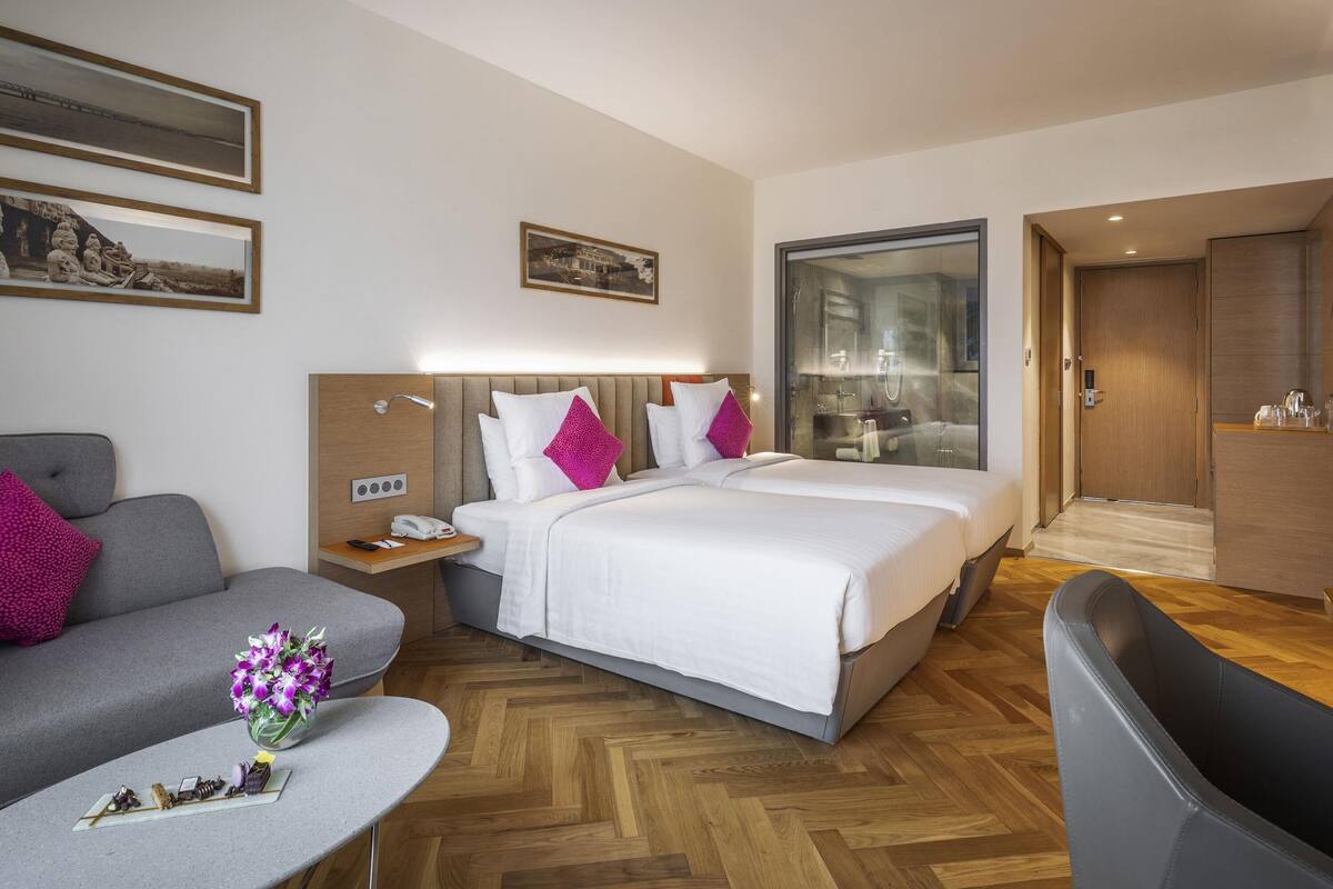 Een hotelkamer met een bed, nachtkastjes, een bureau, een stoel en een bank.