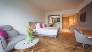 Een moderne hotelkamer met een bed, een bank, een bureau en een eethoek.