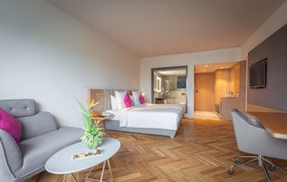Ein modernes Hotelzimmer mit Bett, Sofa, Schreibtisch und Essbereich.