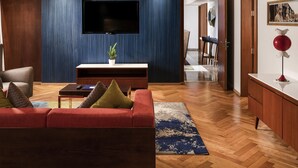 Een moderne woonkamer met een flatscreen televisie, houten paneelwanden, een rode bank en een salontafel.