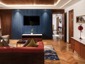 A modern living room with a flat-screen TV, wooden panel walls, a red sofa, and a coffee table.