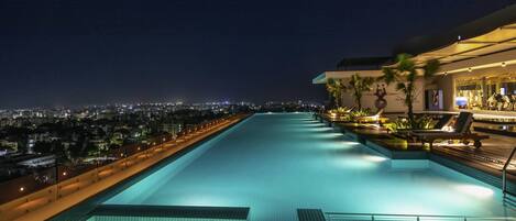 Una piscina al aire libre, sombrillas, sillones reclinables de piscina