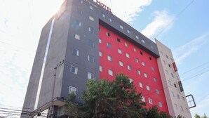 Een hotel met meerdere verdiepingen, een gevel in rood en grijs, en veel ramen, met een bord waarop 